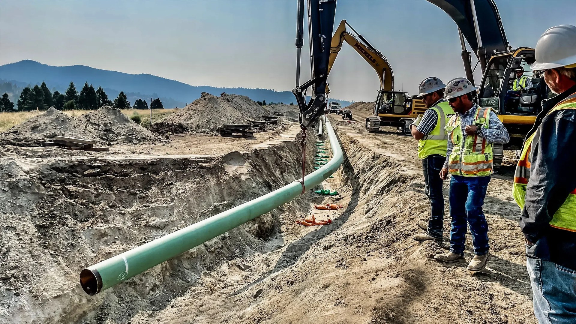 FBE coated steel pipeline being lowered into trench during pipeline construction